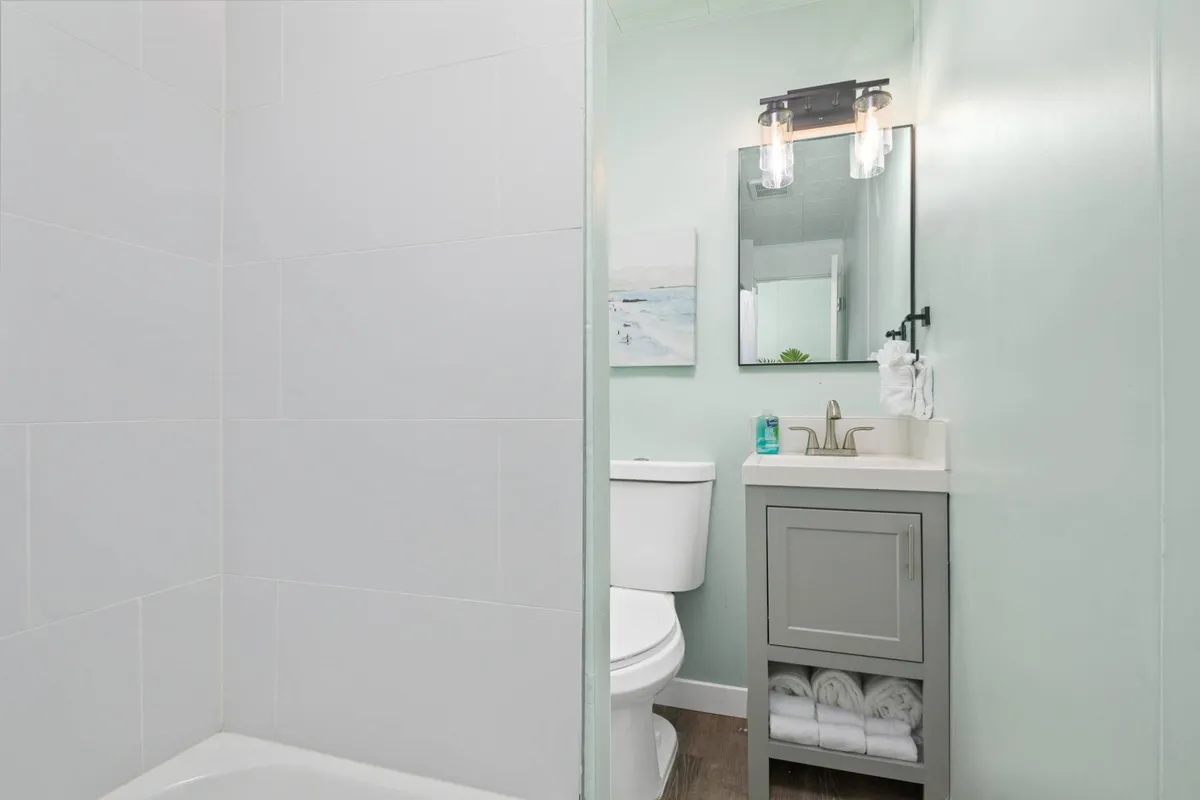 A modern ensuite bathroom showcasing a sleek sink with a contemporary faucet, a large framed mirror, and soft lighting. Tasteful towels and subtle décor contribute to a soothing, inviting feel, emphasizing both convenience and privacy.