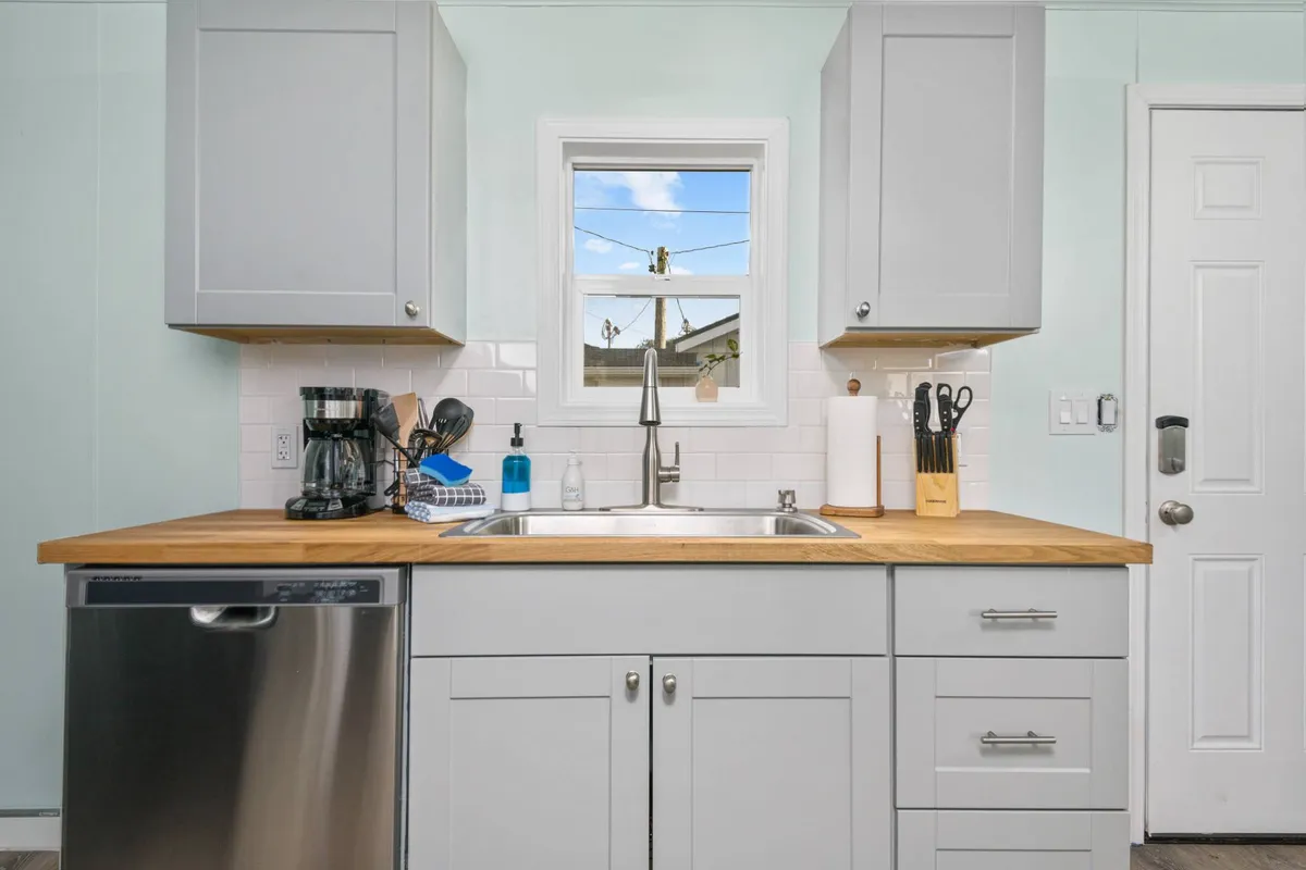 A bright, inviting kitchen space featuring a modern countertop, a coffee maker positioned by a window with natural light, and cooking utensils neatly arranged. The scene evokes a sense of comfort and readiness for morning coffee or meal prep before heading out for the day.